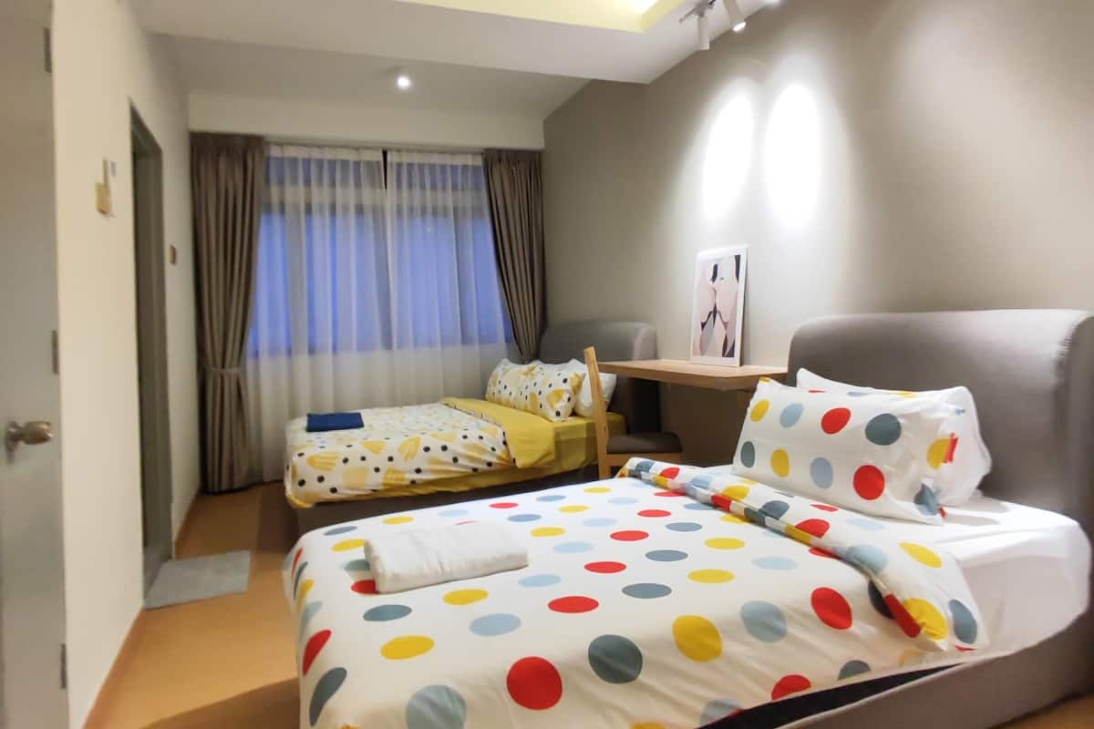 A hotel room with a bed, a desk, a chair, and a ceiling fan.