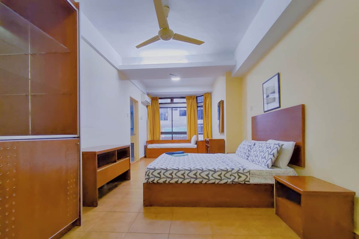 A bedroom with a bed, bedside tables, a ceiling fan, a window with curtains, and a wall-mounted picture.