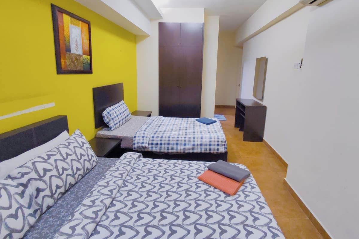 A compact bedroom with two beds, a wardrobe, and a small desk.