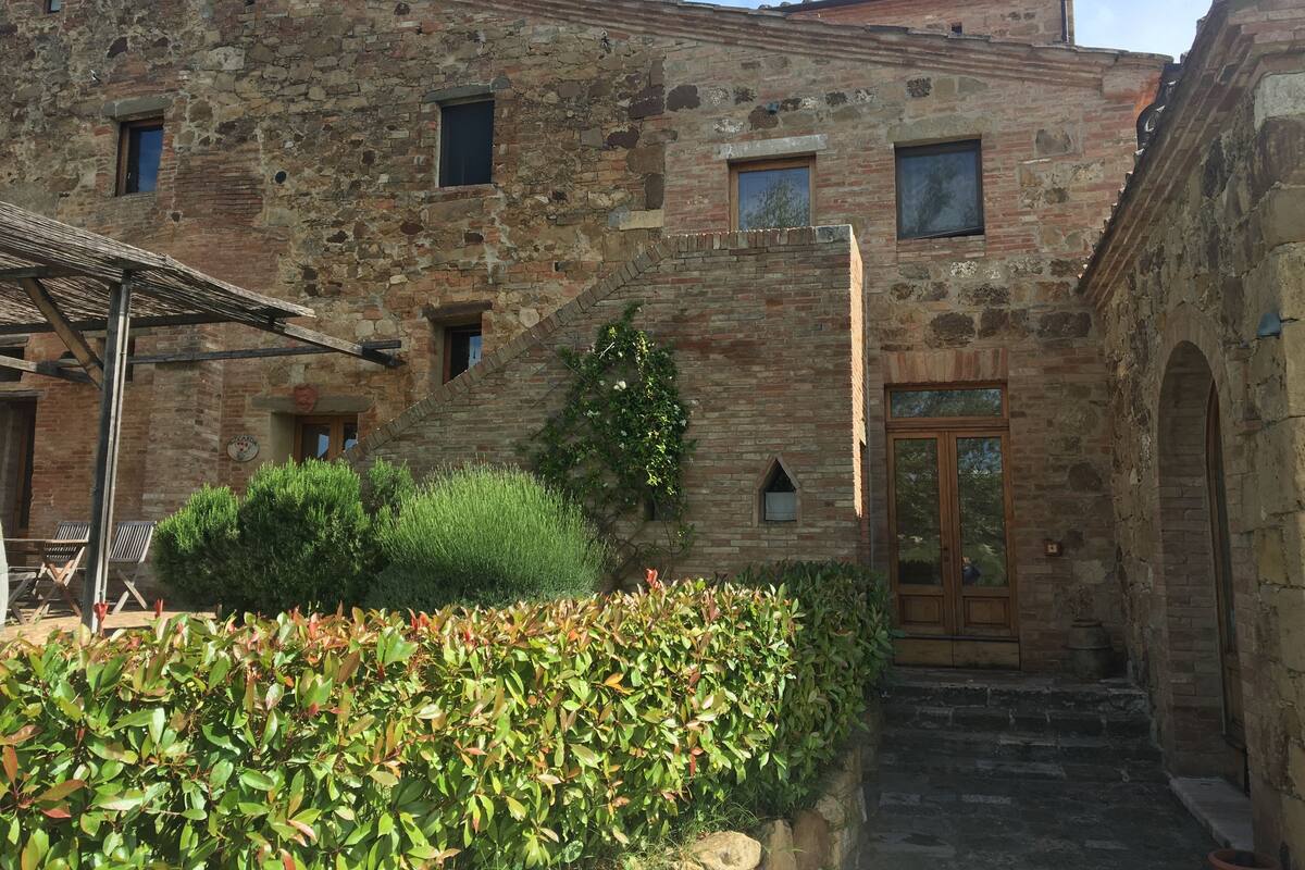 An old stone building with a wooden door, a small window, and a staircase leading to the entrance.