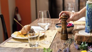 A dining table with a sandwich, a glass of water, a wine glass, and a pepper grinder. - Bio Tenuta di Paganico - I Roggeti (Civitella Paganico)