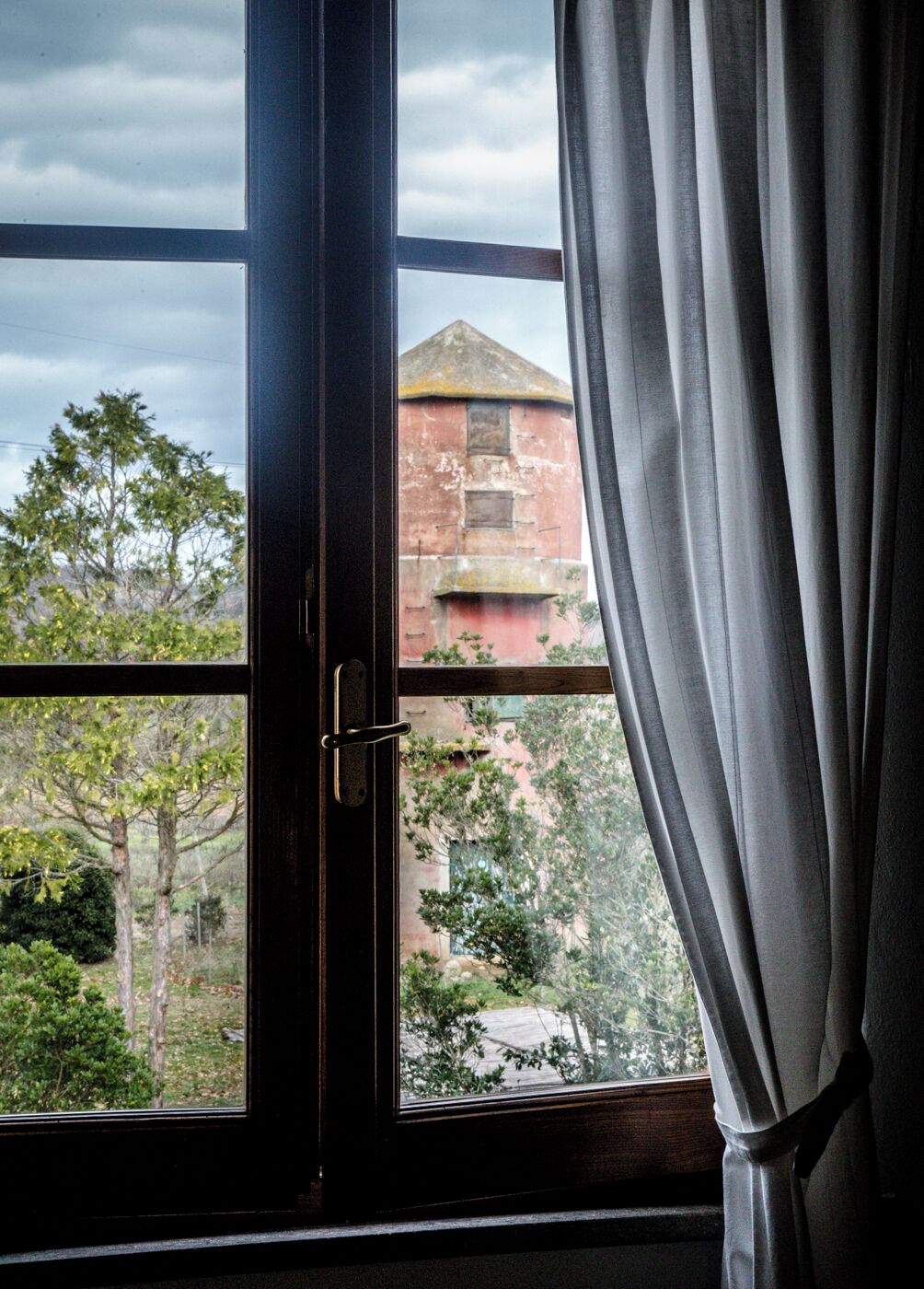 A window with a view of a building and trees.
