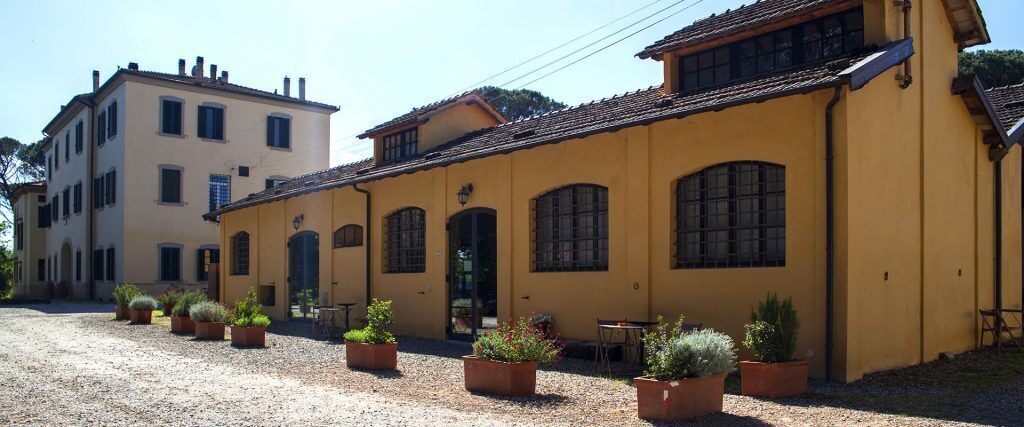 A yellow building with a courtyard, potted plants, and a table.