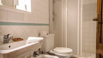 Un bagno con lavandino, bidet, wc e zona doccia.