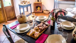 A dining table set with plates, glasses, and a bottle of wine, with a rustic wooden table and a plaid blanket in the background. - Bio Tenuta di Paganico - I Roggeti (Civitella Paganico)