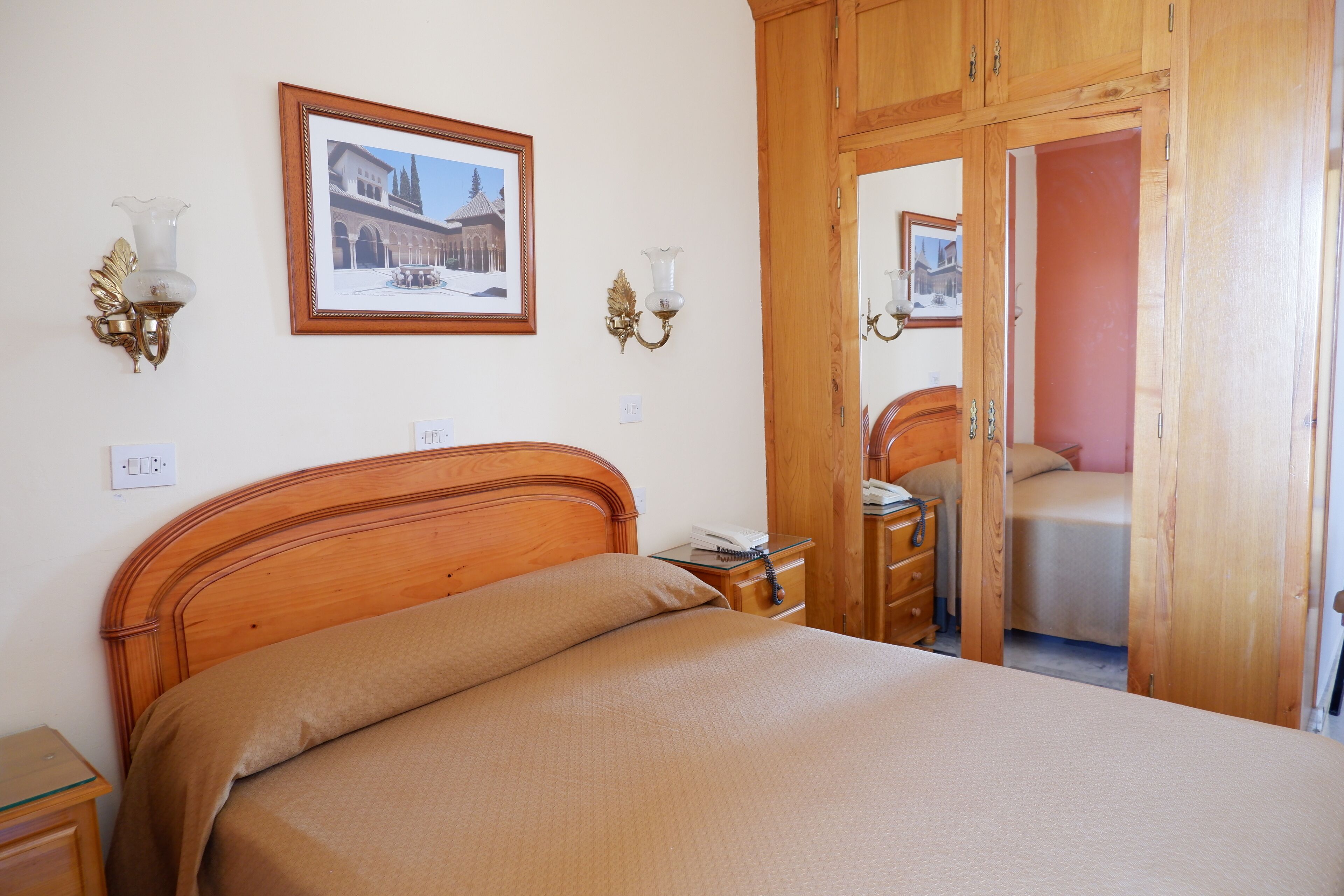 Un dormitorio con cama de madera, mesitas de noche, un armario y un cuadro enmarcado en la pared.