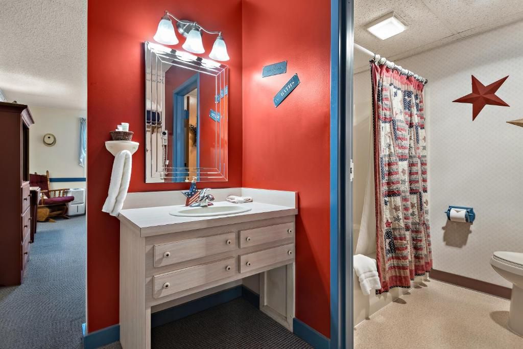 A bathroom with a white sink, mirror, and towel rack. There is a red wall with a star decoration and a blue wall with a star decoration.