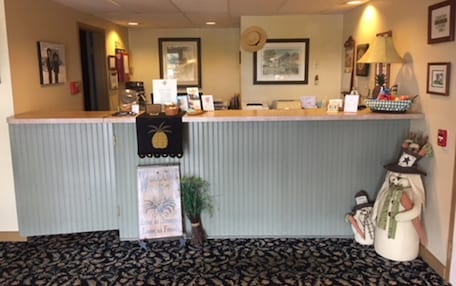 A reception desk with a 'Welcome' sign, framed pictures, and a pineapple decoration.