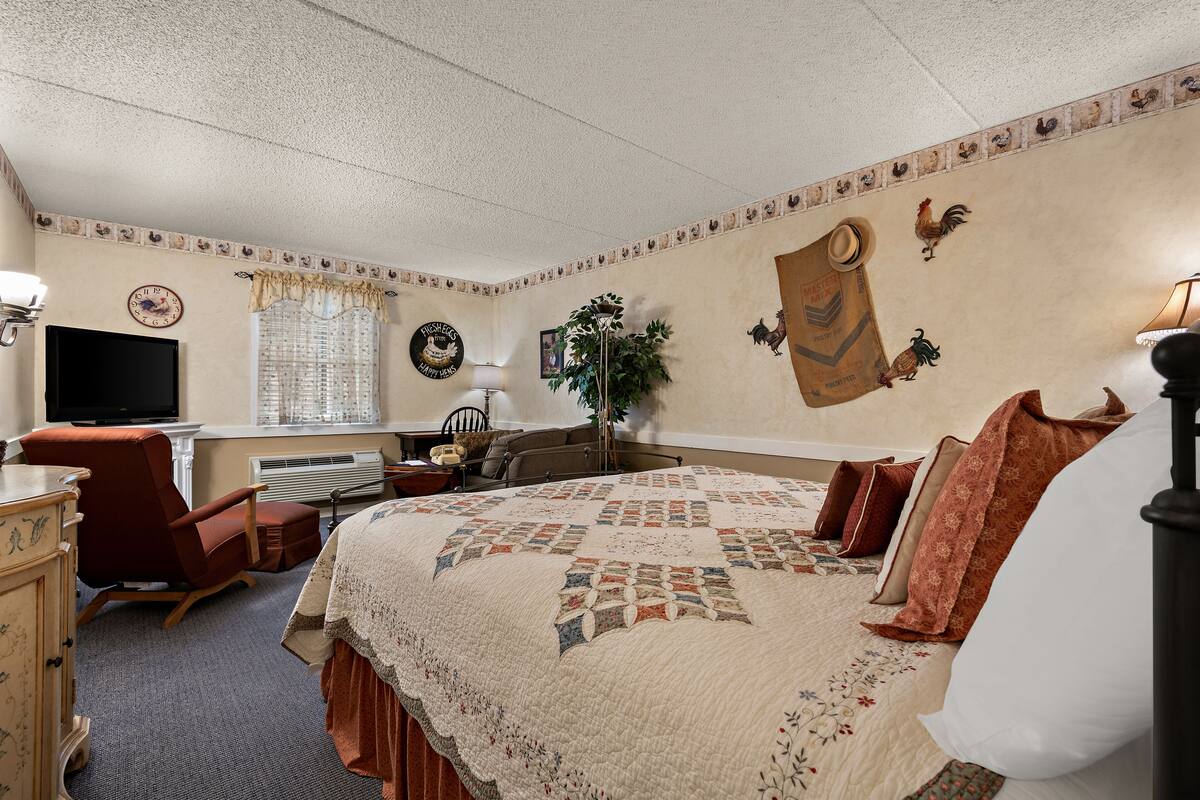 A bedroom with a large bed, a desk with a computer, a chair, and a television.
