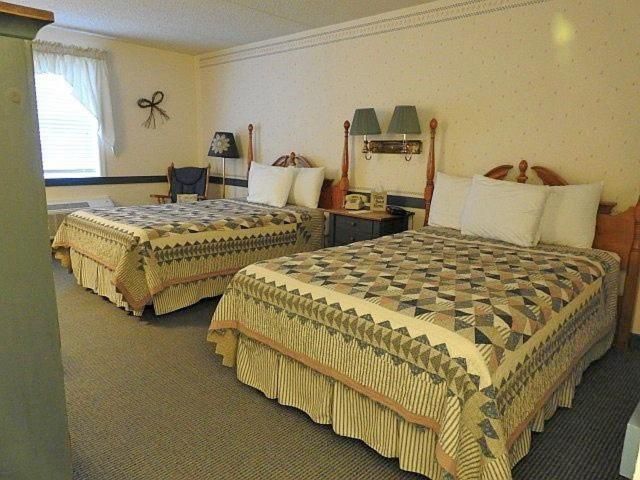 Una habitación de hotel con dos camas, una silla, una mesita de noche y una lámpara.