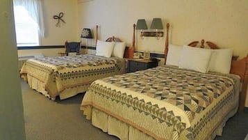 Una habitación de hotel con dos camas, una silla, una mesita de noche y una lámpara.