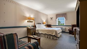 A hotel room with a bed, a desk, a chair, a dresser, and a window with curtains.