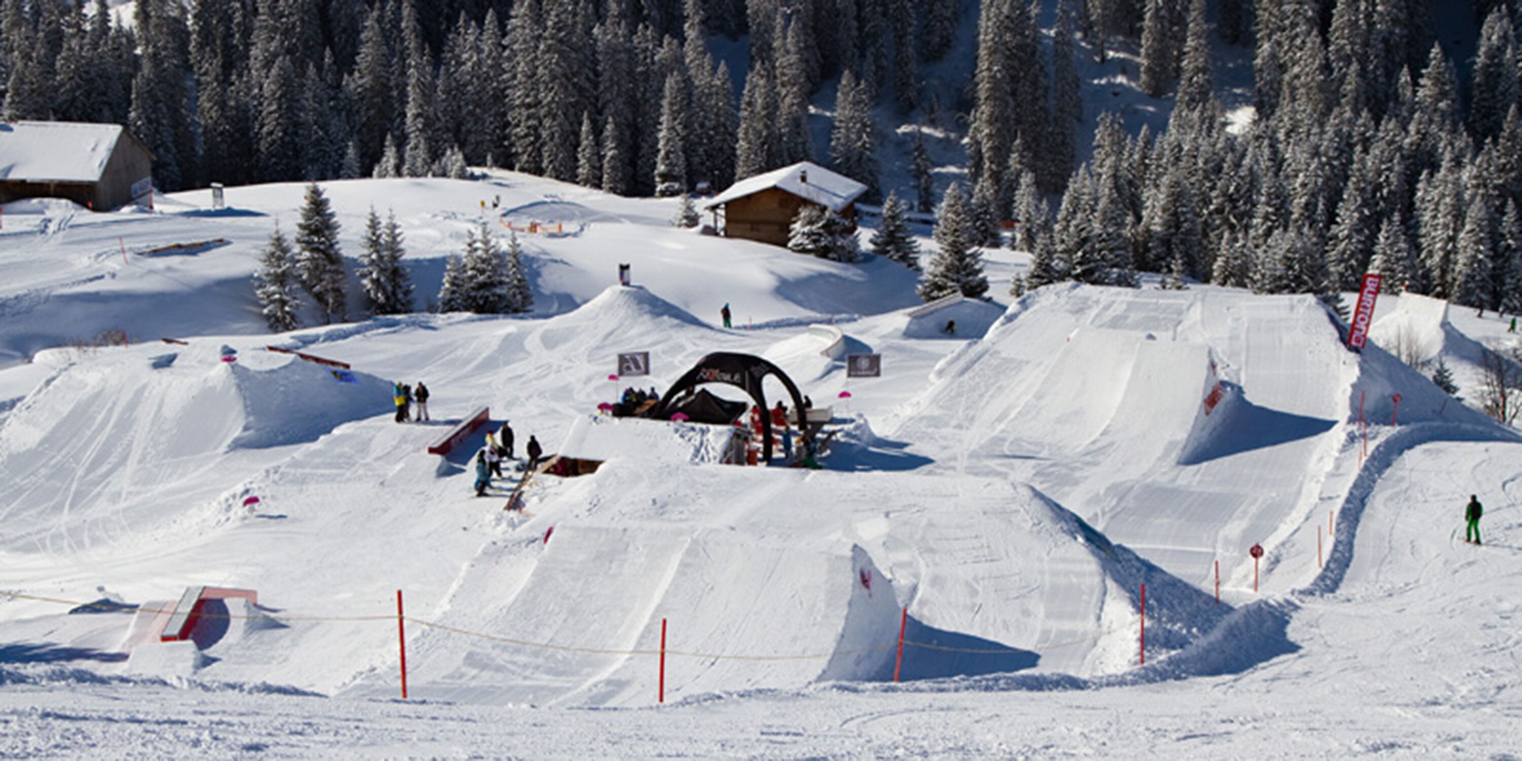 Ein schneebedecktes Skigebiet mit mehreren Pisten, einer Berghütte und einer Seilbahn.