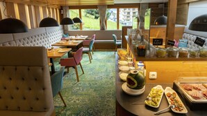 Un comedor de hotel con bufé, disposición de mesas y vistas al exterior.