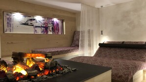 A modern living room with a fireplace, a sofa, and a wall-mounted artwork. - Hotel Lucia (Damüls)