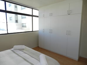 Ein Hotelzimmer mit Bett, Kleiderschrank und Fenster mit Blick auf Gebäude.