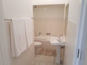 A compact bathroom with a toilet, sink, and shower.