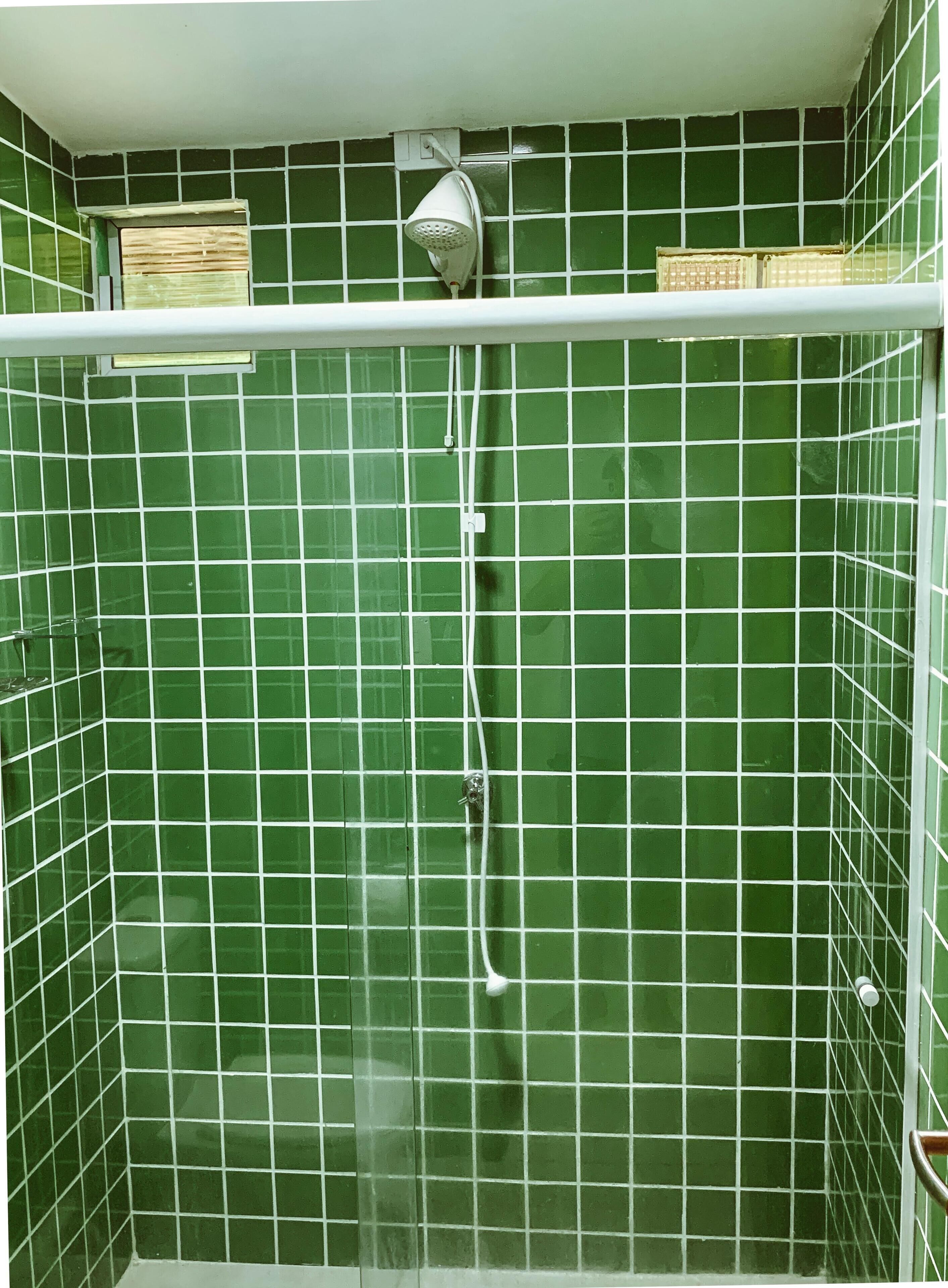 Une douche avec un pommeau de douche blanc et un panneau de commande blanc fixé au mur.