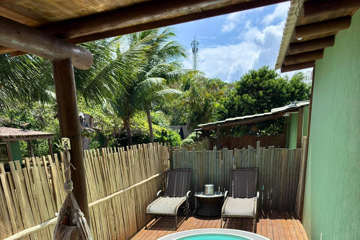 A wooden deck with a hot tub, wicker chairs, and a table.