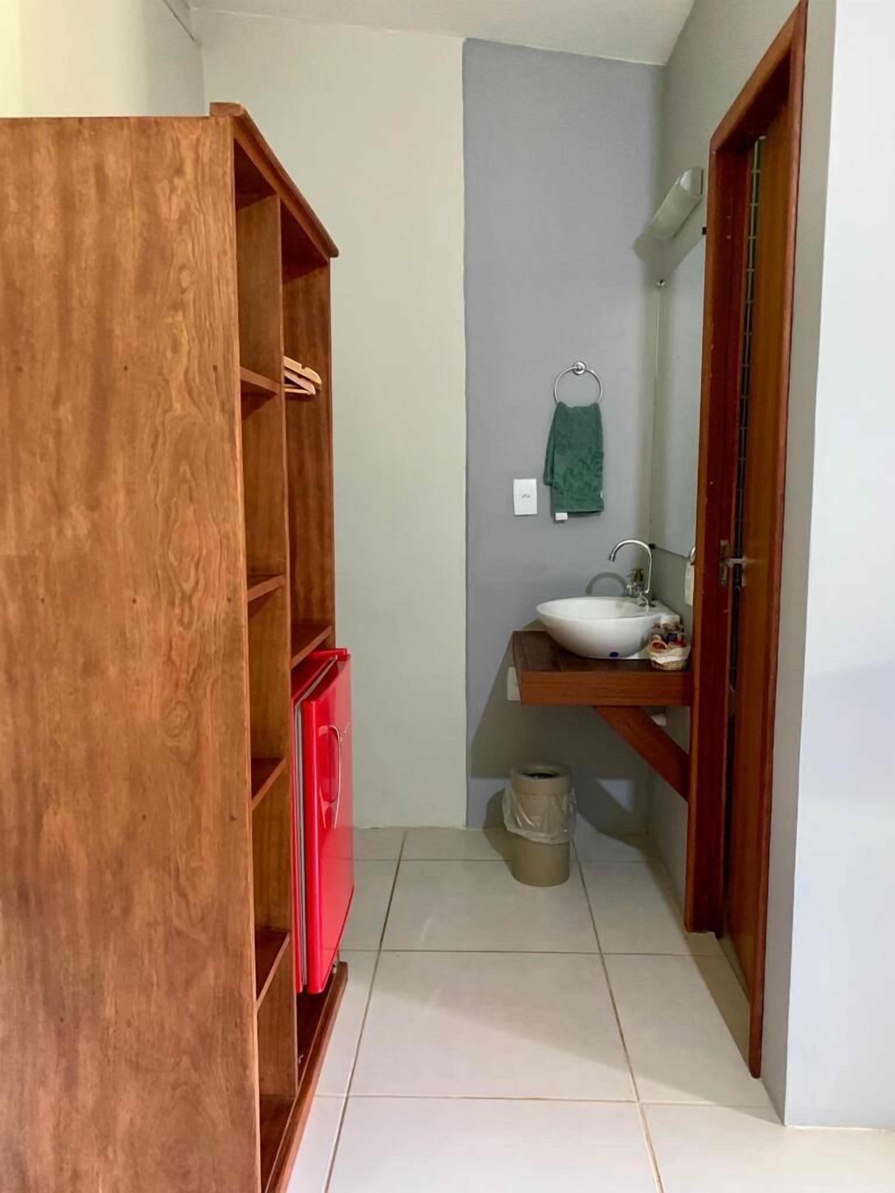A small bathroom with a wooden cabinet, a red cabinet, a sink, and a towel rack.