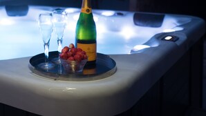 Un jacuzzi con una botella de champán y fresas en una bandeja.