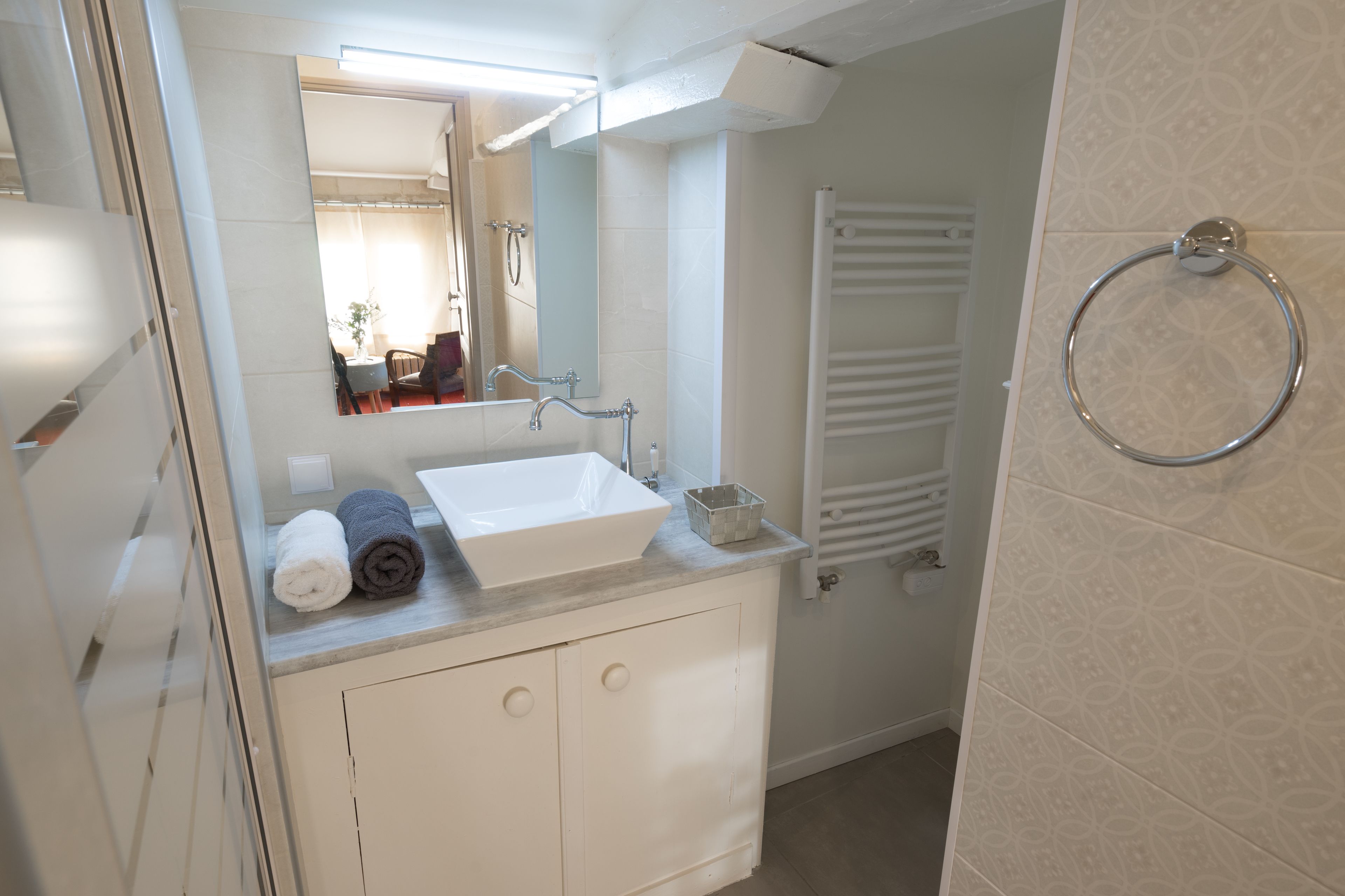 Un bany modern amb un lavabo blanc, un mirall i una barra de tovalloles.