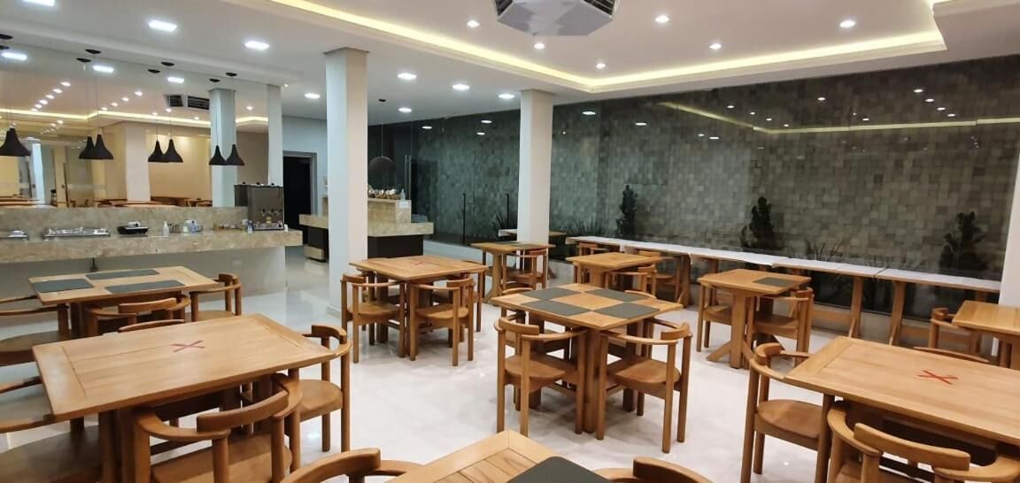 Um restaurante moderno com mesas e cadeiras de madeira, área de bar e uma grande janela com vista.