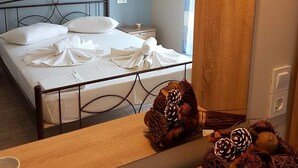 A neatly made bed with white linens, a wooden nightstand with decorative pinecones, and an air conditioning unit on the wall. - Marathon Studios &Apartments (Zakynthos)