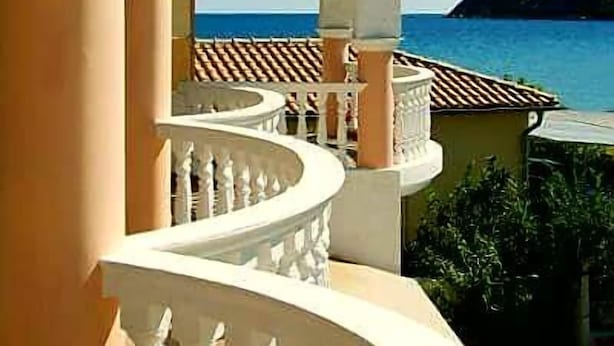 A balcony with a view of the sea, featuring a curved railing and a clear sky. - Marathon Studios &Apartments (Zakynthos)