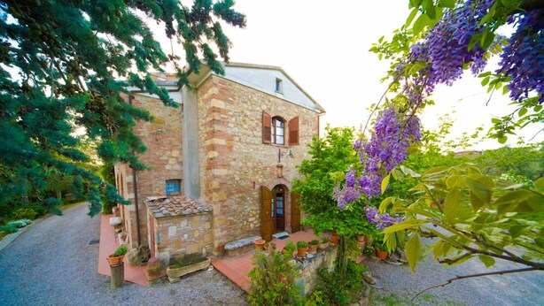 A stone building with a red-tiled roof, a wooden door, and a small porch area with potted plants. - Agriturismo Cognanello (Montepulciano)