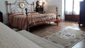 A bedroom with a bed, a dresser, a radiator, and a window with curtains. - Agriturismo Cognanello (Montepulciano)