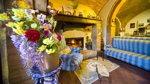 A cozy living room with a fireplace, a sofa, and a large floral arrangement. - Agriturismo Cognanello (Montepulciano)