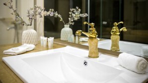 A bathroom with a large white sink, gold faucets, and a mirror reflecting the room. - Pirimze Plaza (Tbilisi)