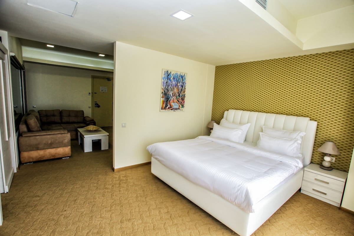 Une chambre d’hôtel avec un grand lit, un canapé, une petite table et un tableau au mur.