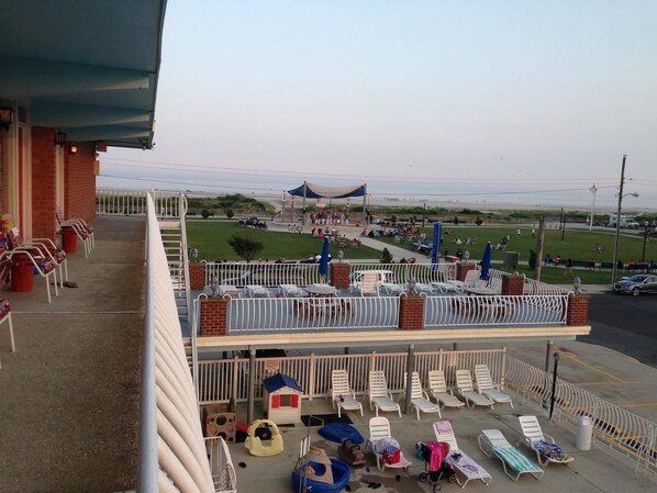 A balcony with lounge chairs, a small playhouse, and a view of the beach.