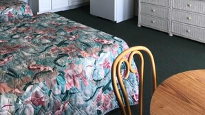 A compact hotel room with a bed, a small kitchenette, a ceiling fan, and a dresser. - Gold Crest Motel (Wildwood Crest)