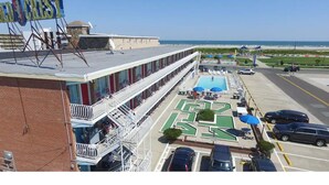 A hotel with a rooftop pool, a parking lot, and a view of the beach. - Gold Crest Motel (Wildwood Crest)