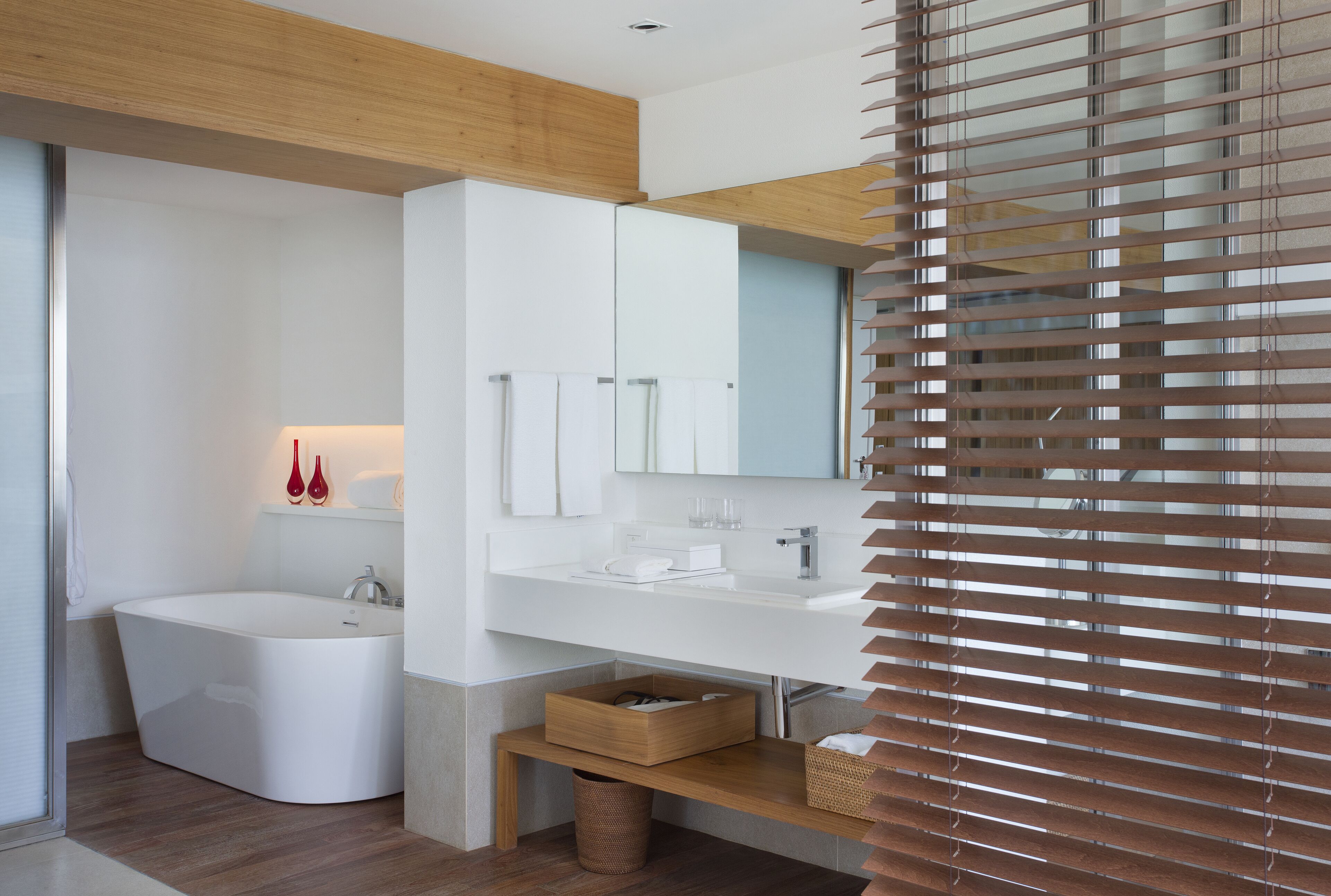 A modern bathroom with a freestanding bathtub, a white vanity, and a large mirror.