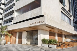 A modern building with the name "JANEIRO" on the facade. It features a covered outdoor seating area with tables and chairs. - JANEIRO Hotel (Rio de Janeiro)