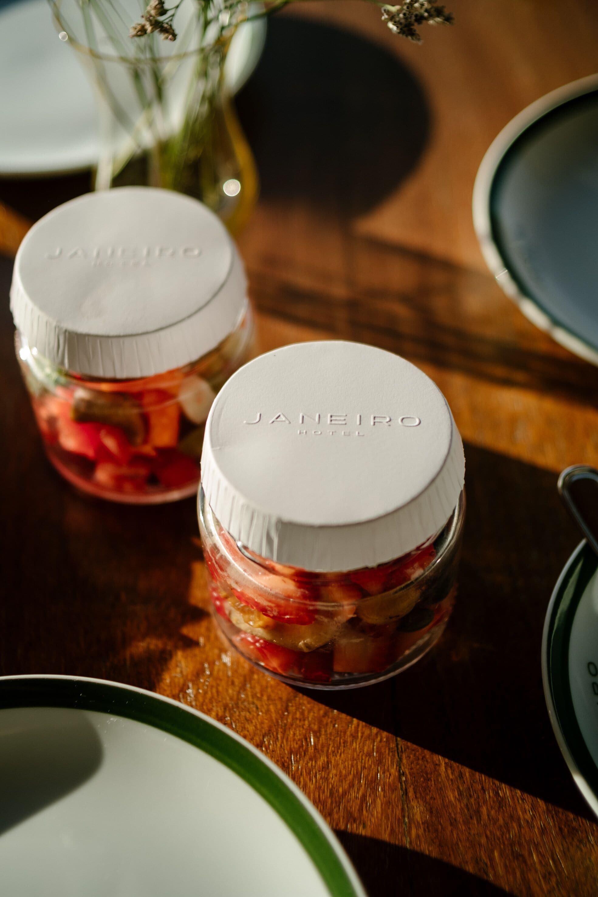 Two jars of jam with white lids labeled "JAIMEIRO HOTEL" on a wooden table.