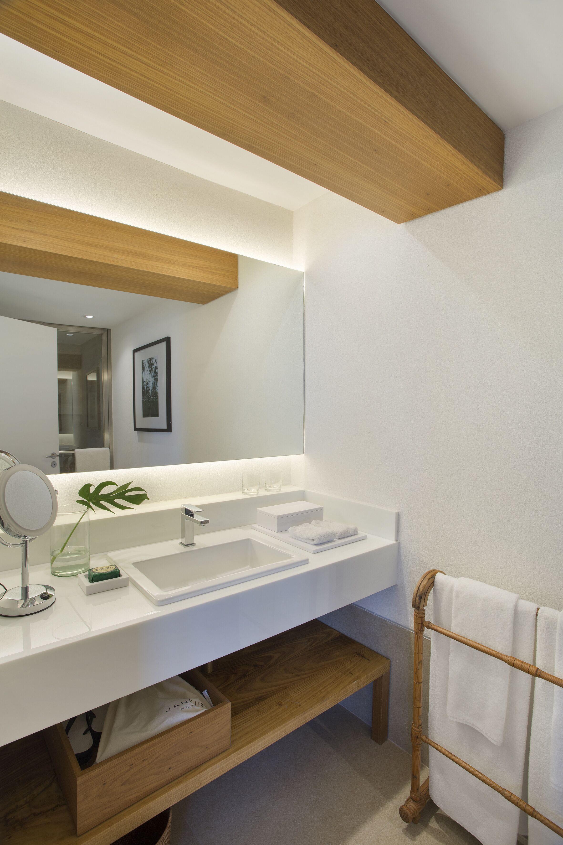 A modern bathroom with a wooden ceiling, a large mirror, two sinks, and a towel rack.
