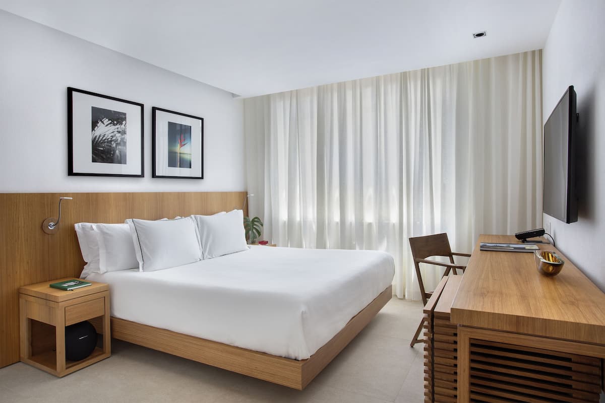 A modern hotel room with a bed, a desk, and a TV.