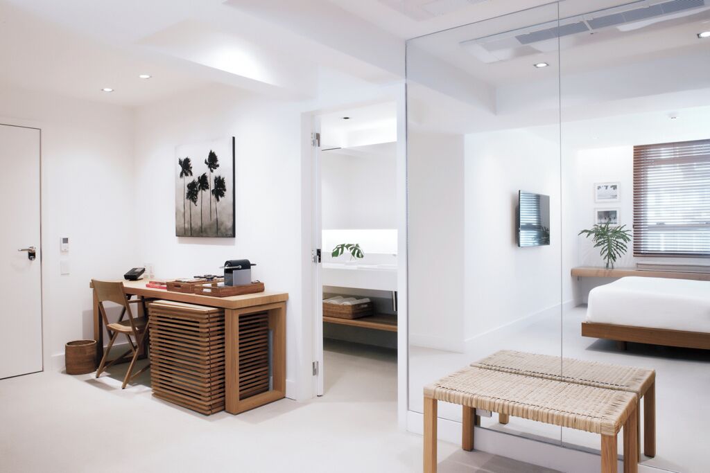 A modern bedroom with a bed, a bedside table, and a window with blinds.