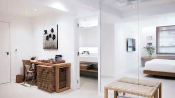 A modern bedroom with a bed, a bedside table, and a window with blinds.