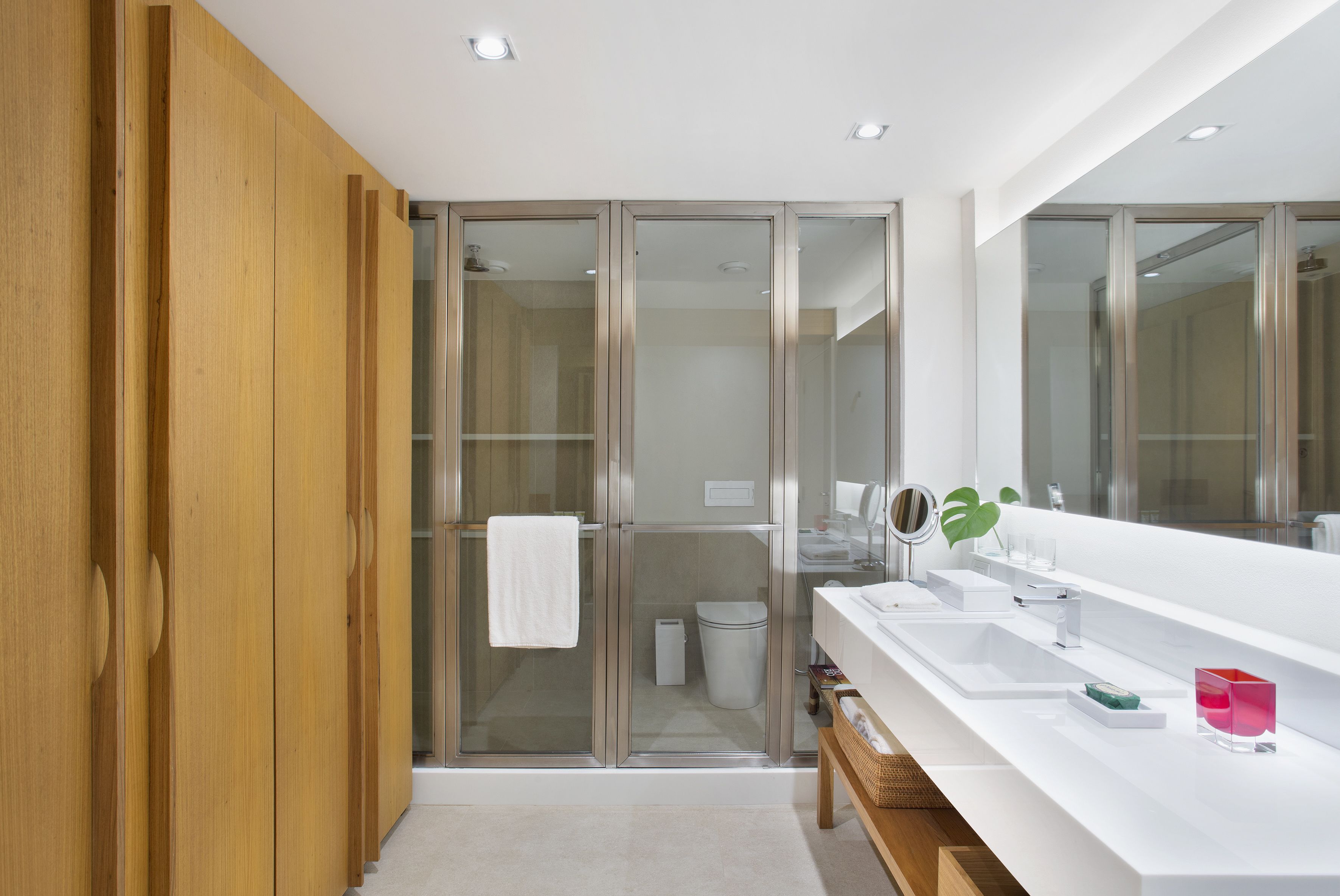 A modern bathroom with a wooden panel wall, a glass shower enclosure, a white sink with a mirror, and a white toilet.