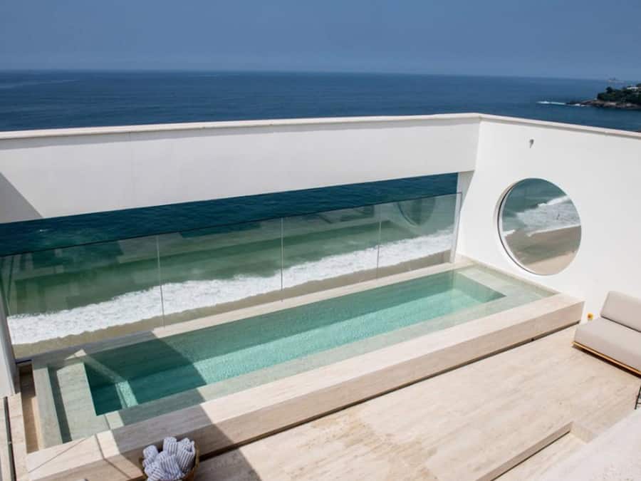 Ein moderner Infinity-Pool mit freiem Blick auf den Ozean, einem runden Fenster und einem minimalistischen Design.