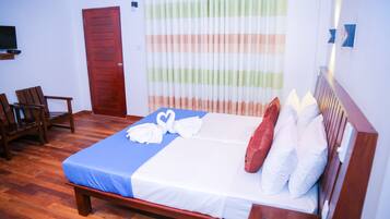 A neatly made bed with white and red pillows, a blue bedspread, and a heart-shaped towel arrangement. There is a wooden bench and a chair in the room.
