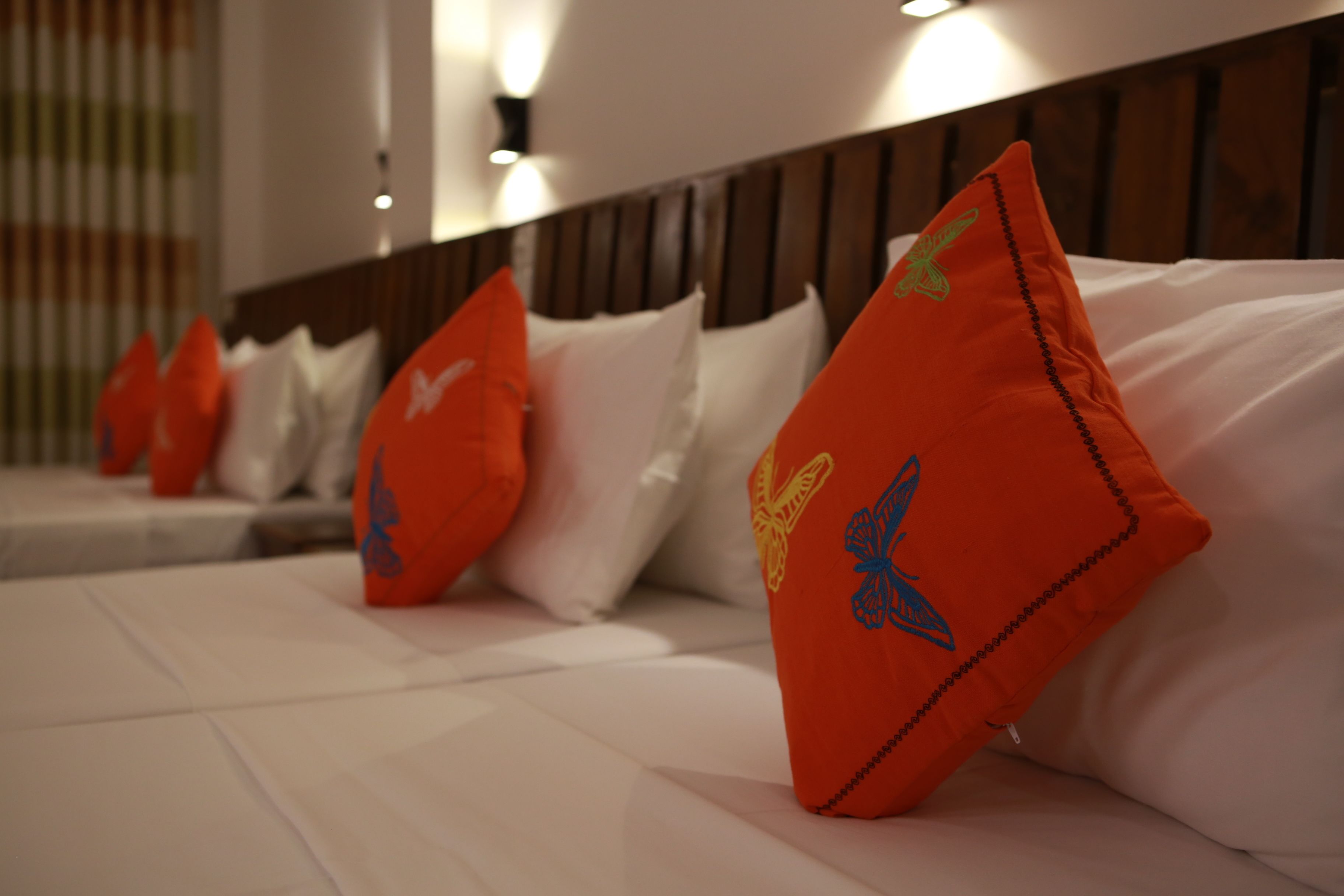 A row of beds with white and orange pillows, some with butterfly designs.