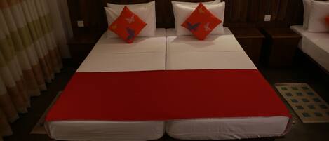 A double bed with a red bedspread and two pillows with butterfly designs.