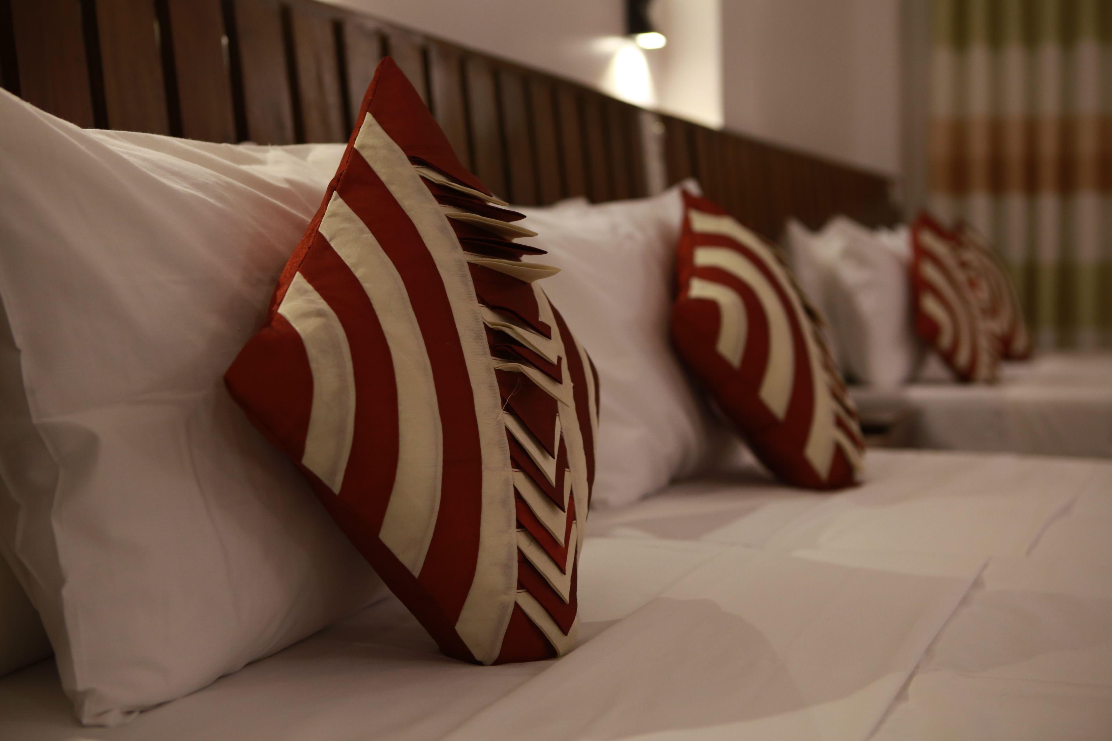 A hotel room with neatly arranged pillows and a wooden headboard.